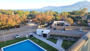 Un quartier résidentiel avec une piscine, des voitures garées et une vue sur une chaîne de montagnes.