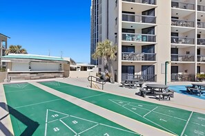 A courtyard with shuffleboard courts, outdoor seating, and a pool area.