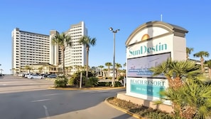 A hotel sign with 'SunDestin' and 'Beach Resort' text, a parking lot, and tall buildings in the background.