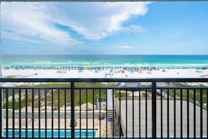 Une vue sur la plage depuis un balcon, avec une piscine et une balustrade.