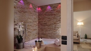 A modern bathroom with a stone wall, a bathtub, a vanity with a plant, and a towel rack. - Villa Antica Dimora intera struttura - Homelike Villas (San Donato)