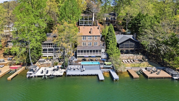 Una proprietà sul lago con un molo, una piscina e diversi edifici immersi nel verde.