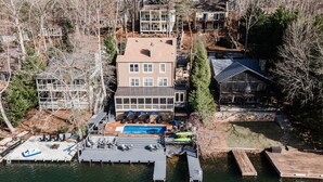 Una proprietà sul lago con una casa grande, un molo e una piscina.