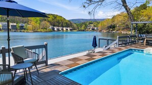Una piscina con solarium, sedie e ombrellone.