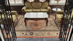 Um quarto com um conjunto de sofá antigo, uma mesa de centro e um tapete estampado.