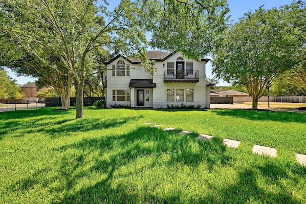 A two-story house with a front porch, a balcony, and a well-maintained lawn.