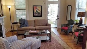 A living room with a sofa, armchair, and ottoman, a coffee table, and a fireplace.