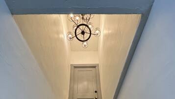 Una escalera con escalones azules, barandilla de madera y un candelabro.