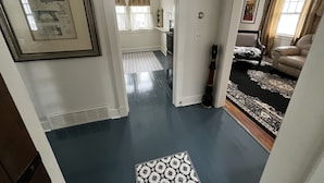 A hallway with a patterned rug, a framed picture on the wall, and a door leading to another room. - Charming Carriage House near VanderVeer Park (Davenport)