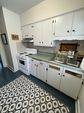 Une cuisine avec des meubles blancs, une cuisinière et un évier.