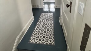 A hallway with a patterned carpet, a welcome sign, a mirror, and a door leading to another room. - Charming Carriage House near VanderVeer Park (Davenport)