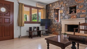 Ein Wohnzimmer mit Steinwand, Kamin, Fernseher und Holztisch.