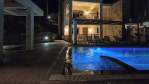 Ein modernes, zweistöckiges Haus mit Schwimmbad bei Nacht.