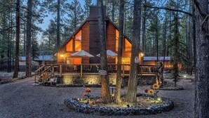 A cabin with a wooden exterior, a deck, and a gravel driveway.