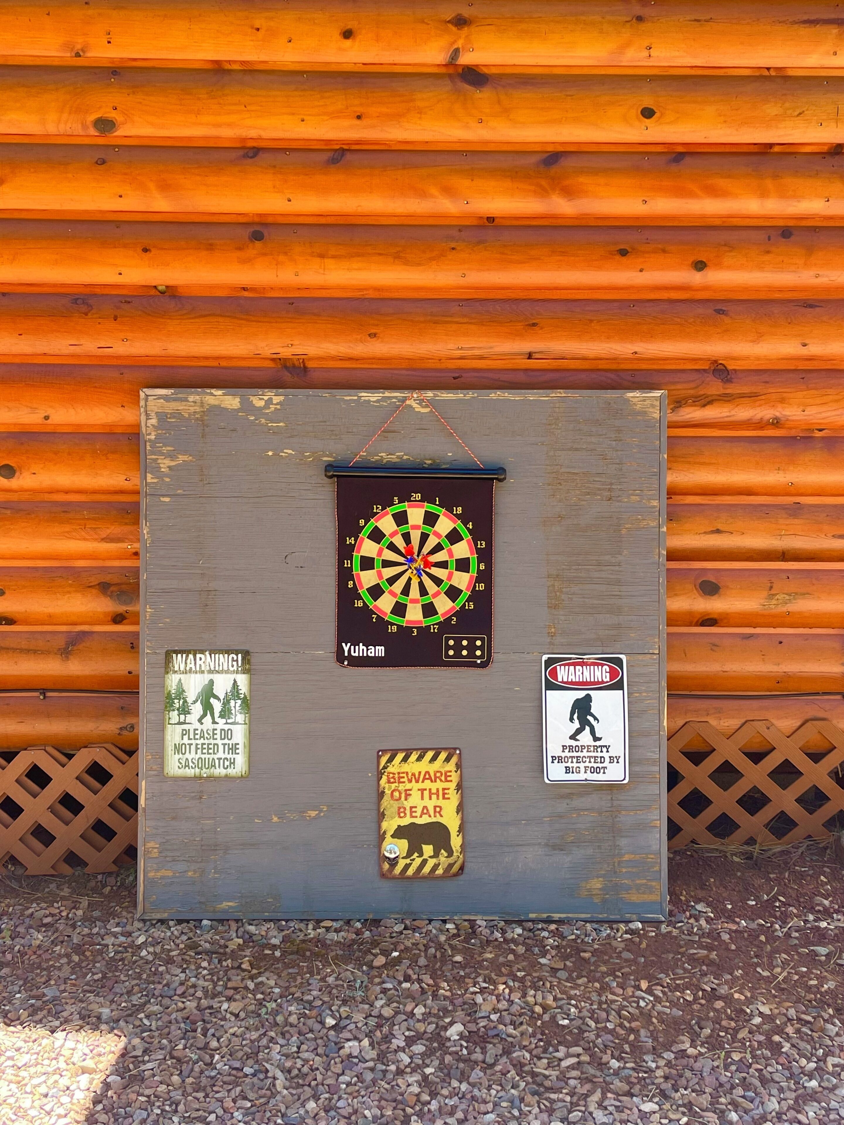 Een houten plank met een dartbord, waarschuwingstekens en een advertentie voor beren.