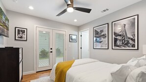 Una camera da letto con un letto, una ventola a soffitto e quadri appesi al muro.