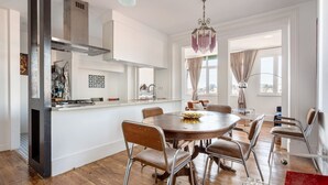 A modern kitchen with a central island, stainless steel appliances, and a dining area with a round table and chairs. - JOIVY Cosy 2-bed flat w/desk in Arroios (Lisbon)