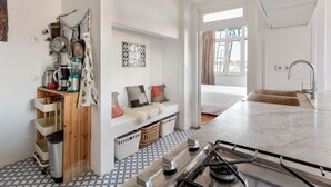 A modern kitchen with a gas stove, a sink, and a window providing natural light. - JOIVY Cosy 2-bed flat w/desk in Arroios (Lisbon)