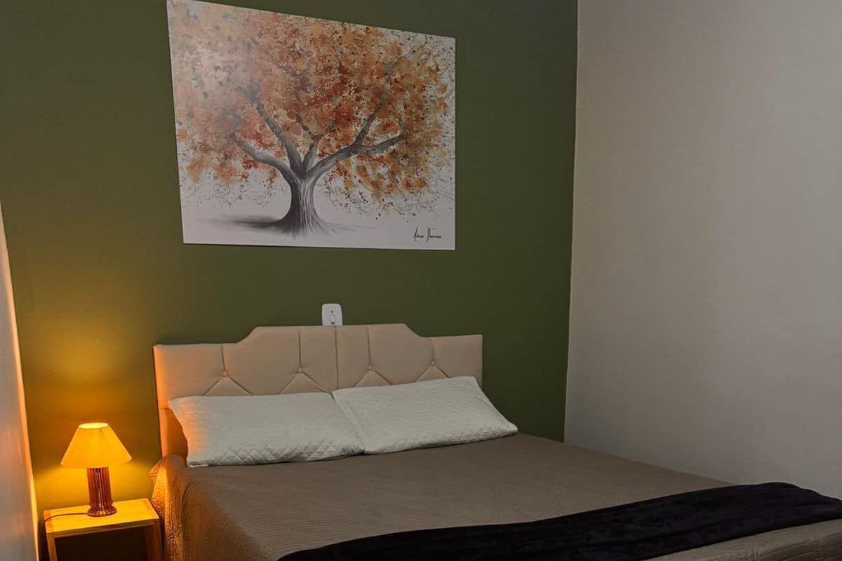 Ein Schlafzimmer mit einem Bett, einem Nachttisch, einer Lampe und einem Bild an der Wand.