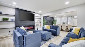 A modern living room with a flat-screen TV, blue sofas, and a fireplace.