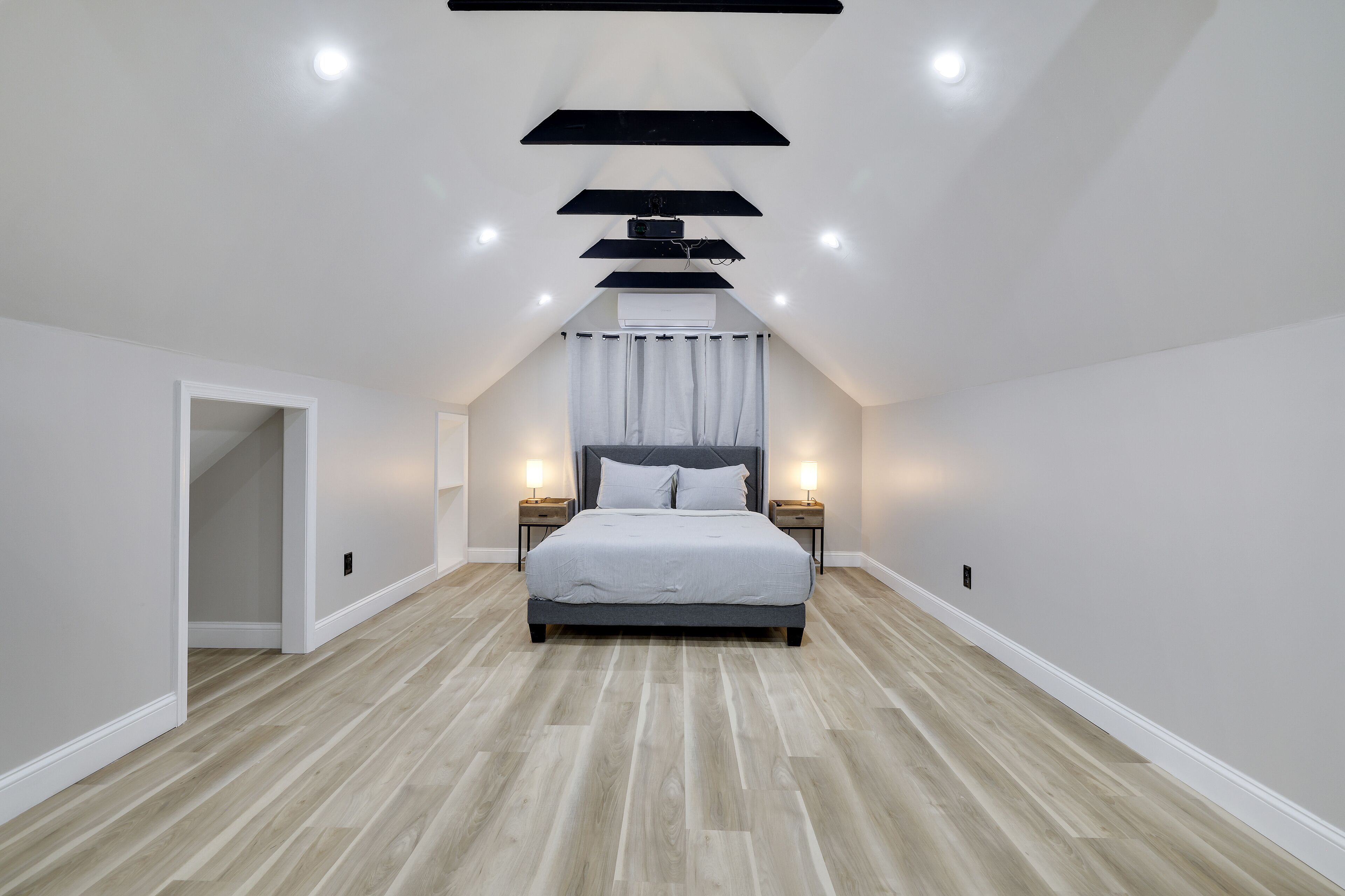 A bedroom with a large bed, two bedside tables, and a ceiling light fixture.