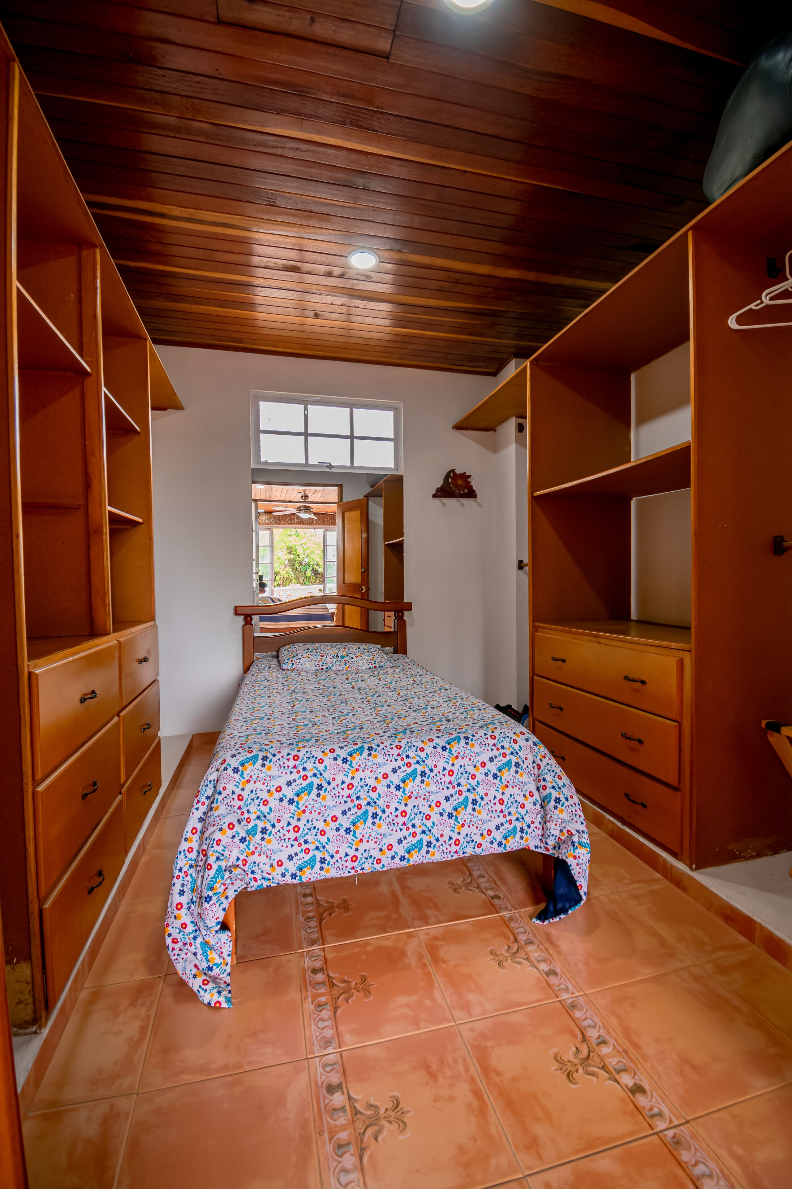 Un dormitorio con cama, armario de madera y ventana.