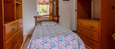 Un dormitorio con cama, armario de madera y ventana.