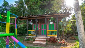 Un parque infantil colorido con una estructura para escalar y un pequeño edificio con porche.