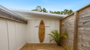 Een klein, afgesloten buitenterras met een houten surfboard decoratie, een palmplant en een gestructureerde vloer.
