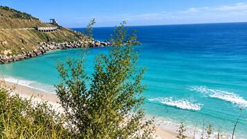 Un paisaje costero con vista despejada al océano, una playa arenosa y un litoral rocoso.
