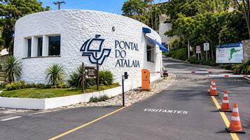Un edificio bianco con un cartello che riporta la scritta 'PONTAL DO ATALAIA' e un logo blu. Sulla strada di fronte ci sono coni stradali arancioni.