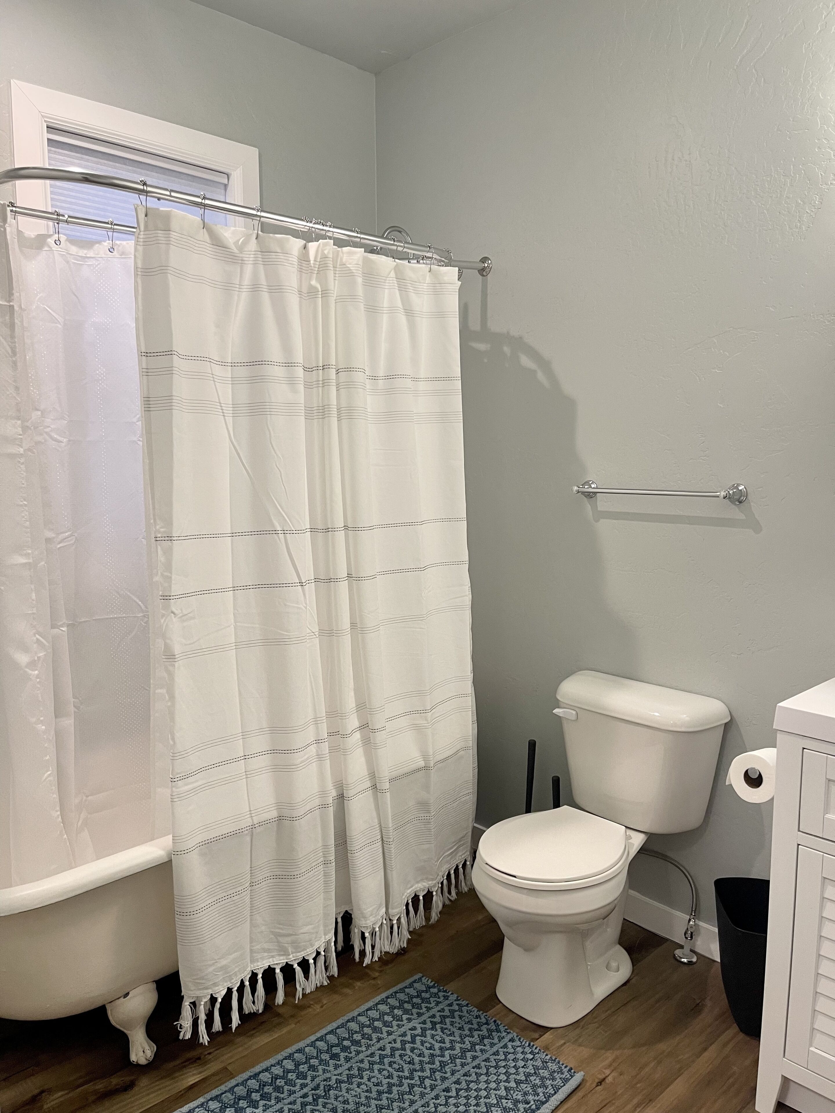 A bathroom with a bathtub, toilet, and a shower curtain.