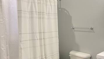 A bathroom with a bathtub, toilet, and a shower curtain.