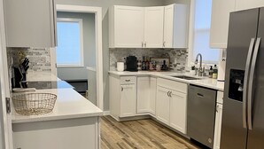 A modern kitchen with white cabinets, a stainless steel refrigerator, and a wooden floor. - NEW! Heart of Downtown: The Hill Oasis (Grand Junction)