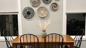 A dining area with a wooden table and four chairs, a vase with dried plants, and decorative wall art. - NEW! Heart of Downtown: The Hill Oasis (Grand Junction)