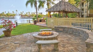 Ein Steinkamin mit Bank, ein Gazebo mit Strohdach und ein Poolbereich mit Zaun.