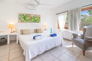 A bedroom with a bed, bedside lamps, a ceiling fan, a window with curtains, and a chair.