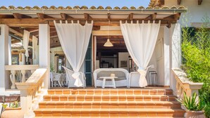 A hotel entrance with a covered porch, outdoor seating, and steps leading to the entrance. - Ca na Tinta - with private swimming pool (Algaida)