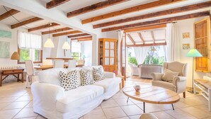 A spacious living room with a white sofa, a round coffee table, and a wooden cabinet. - Ca na Tinta - with private swimming pool (Algaida)