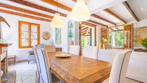 A dining area with a wooden table, white chairs, and pendant lights. - Ca na Tinta - with private swimming pool (Algaida)