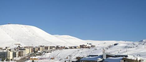 A snow-covered mountain with a ski resort and buildings at the base.