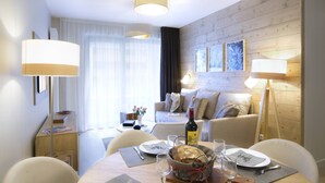 A well-lit dining area with a wooden table set for two, a bottle of wine, and a basket of bread.