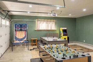 A recreational room with a foosball table, a pool table, and a basketball arcade.