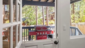 Une vue à travers une porte, avec un barbecue visible à l’extérieur.