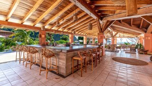 Ein überdachter Außenbereich mit Bar, Holzmöbeln und Blick aufs Meer.