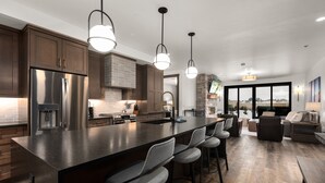 Une cuisine moderne dotée d’un grand  îlot central, de tabourets de bar et d’un mur d’accent en pierre.