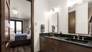 Une salle de bain moderne avec un double vasque, un meuble-lavabo en bois foncé et un grand miroir.