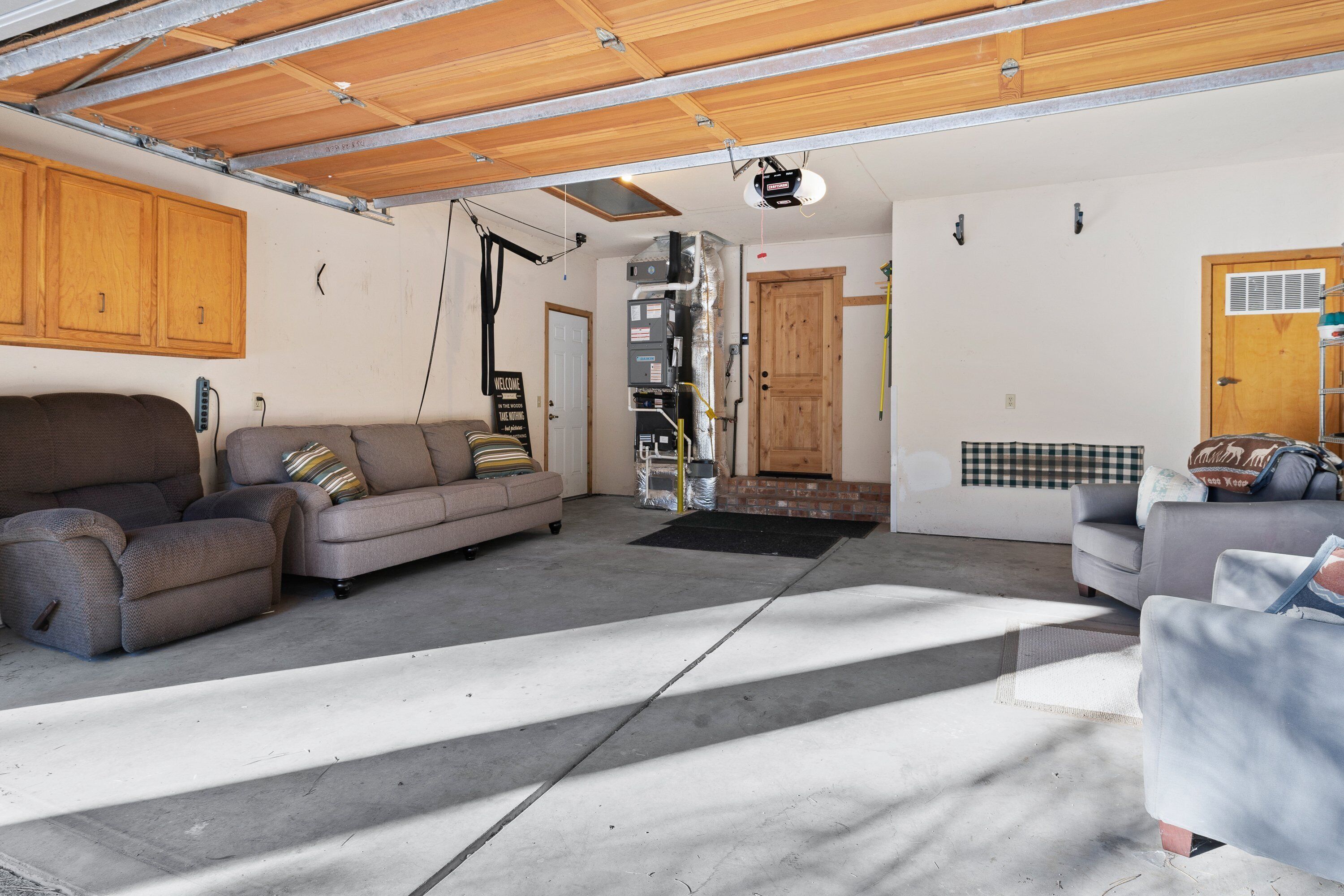 A spacious garage with two sofas, a wooden ceiling, and a door leading to another room.