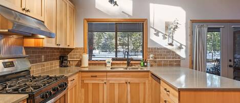 A kitchen with wooden cabinets, a gas stove, a sink, and a window with blinds.