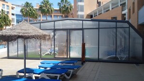 Un espace aménagé au bord de la piscine, avec des chaises longues et un coin salon abrité.